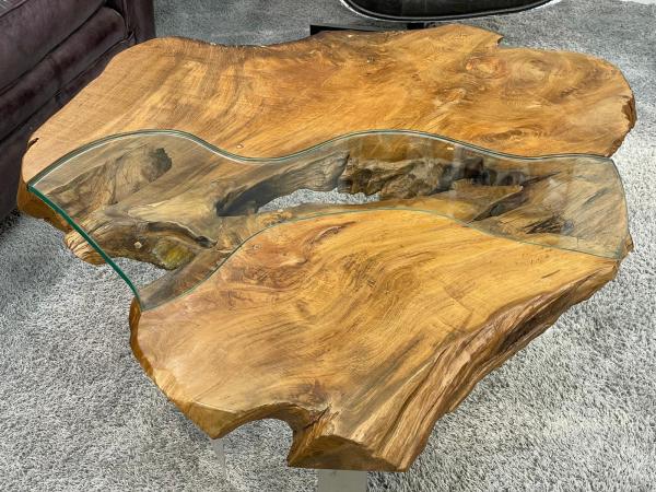 Tree trunk coffee table with glass top, irregular shape.