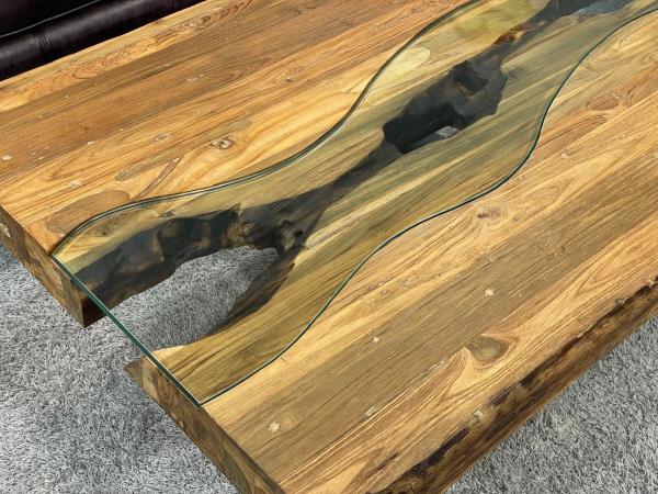 Wohnzimmertisch mit gekreuztem Edelstahlgestell und Holzplatte.