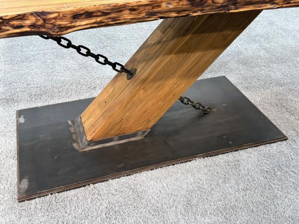 Holz-Esstisch mit Metallkette und rechteckigem Fuß.