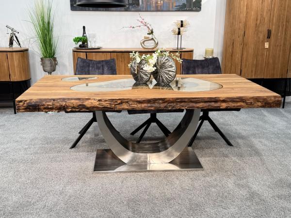 Esstisch aus recyceltem Altholz mit Edelstahlgestell und Glaseinlage.