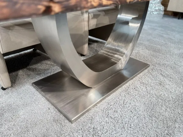Metal base of a dining table with glass inlay on carpet.