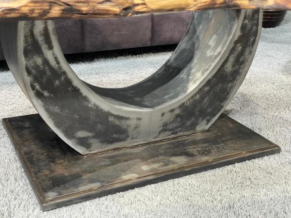 Oval coffee table with organic metal base on carpet.
