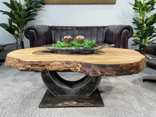 Oval wooden table with glass top and vase with pink flowers.