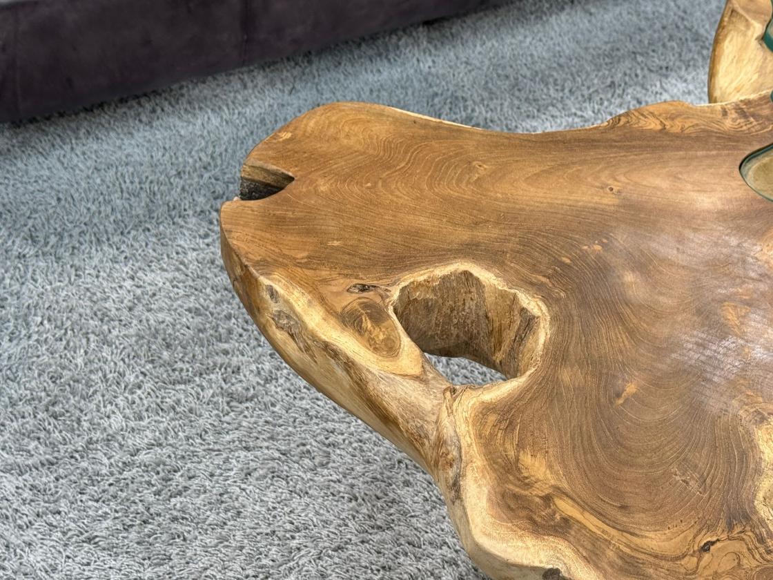 Teakholz-Couchtisch mit organischer Form auf Teppich.