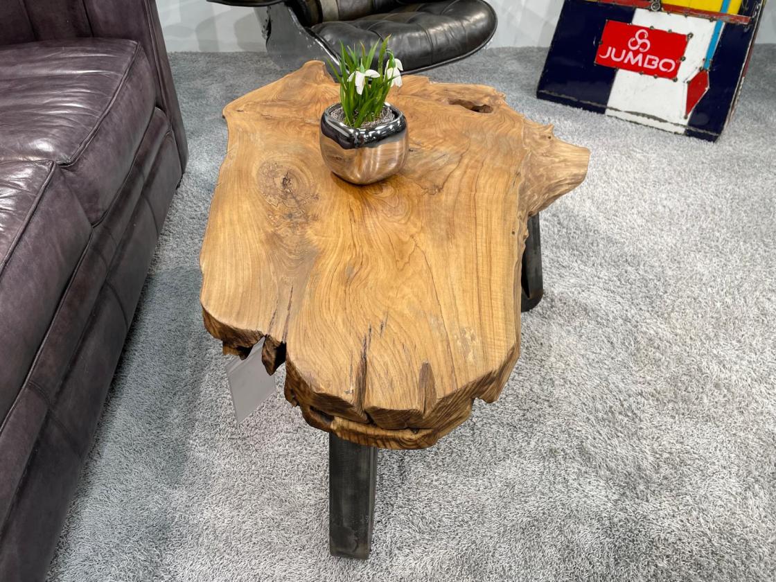 Couchtisch aus Baumstamm mit unregelmäßiger Form und Blumen darauf.