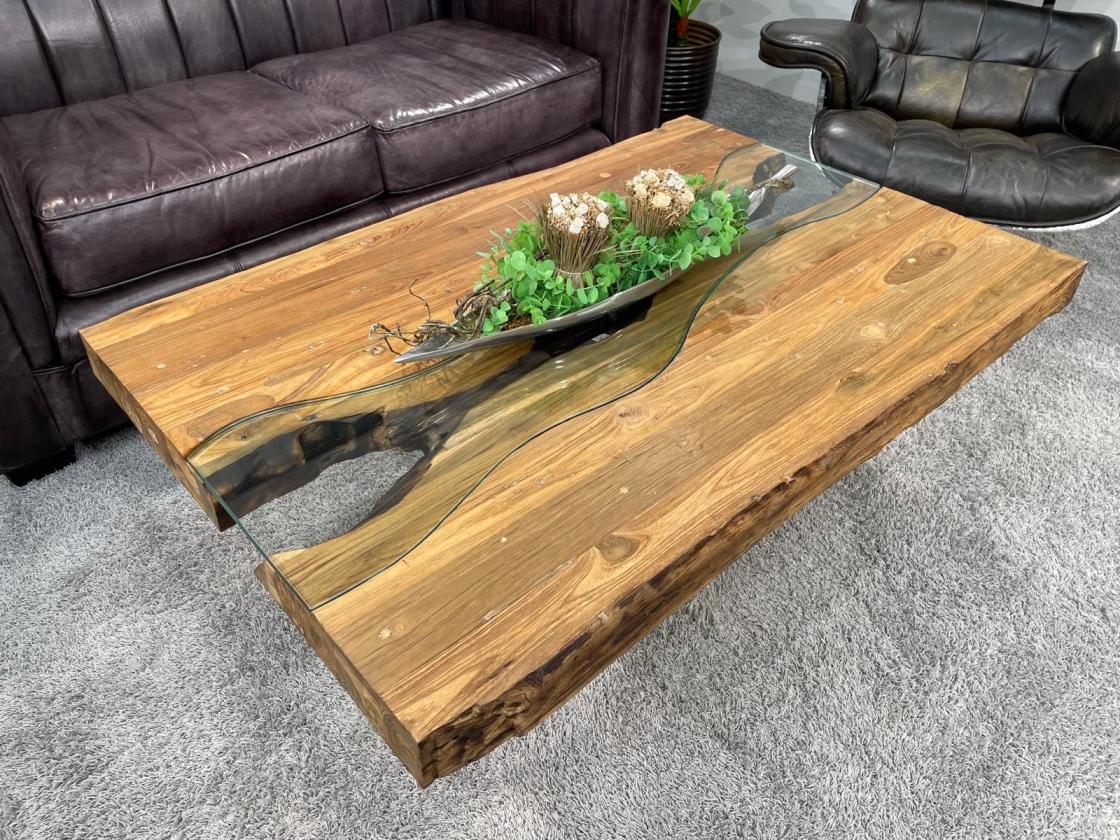 Wohnzimmertisch mit Glasplatte und Edelstahlkreuzgestell.