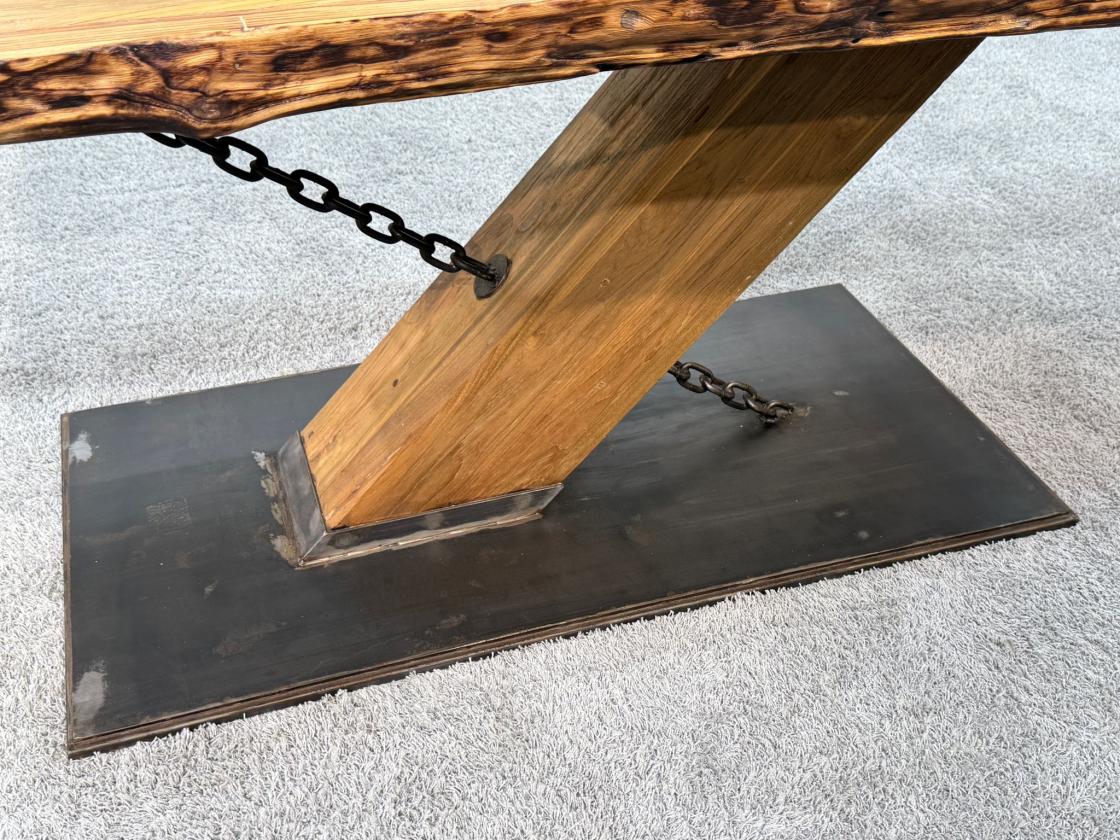 Holz-Esstisch mit Metallkette und rechteckigem Fuß.