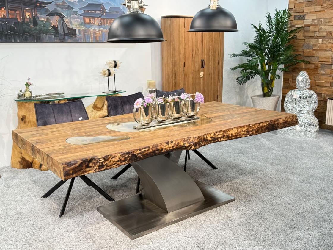 Massivholztisch aus recyceltem Altholz mit Baumstammbeinen.