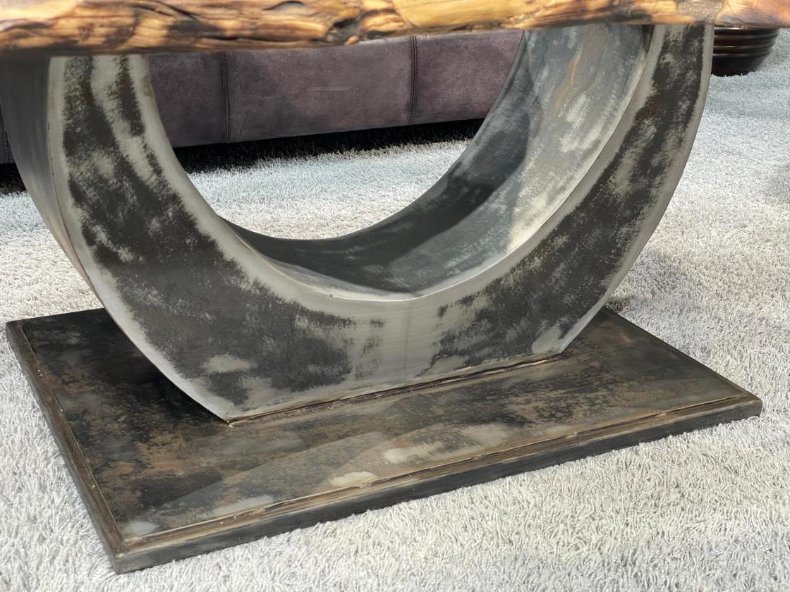 Oval coffee table with organic metal base on carpet.