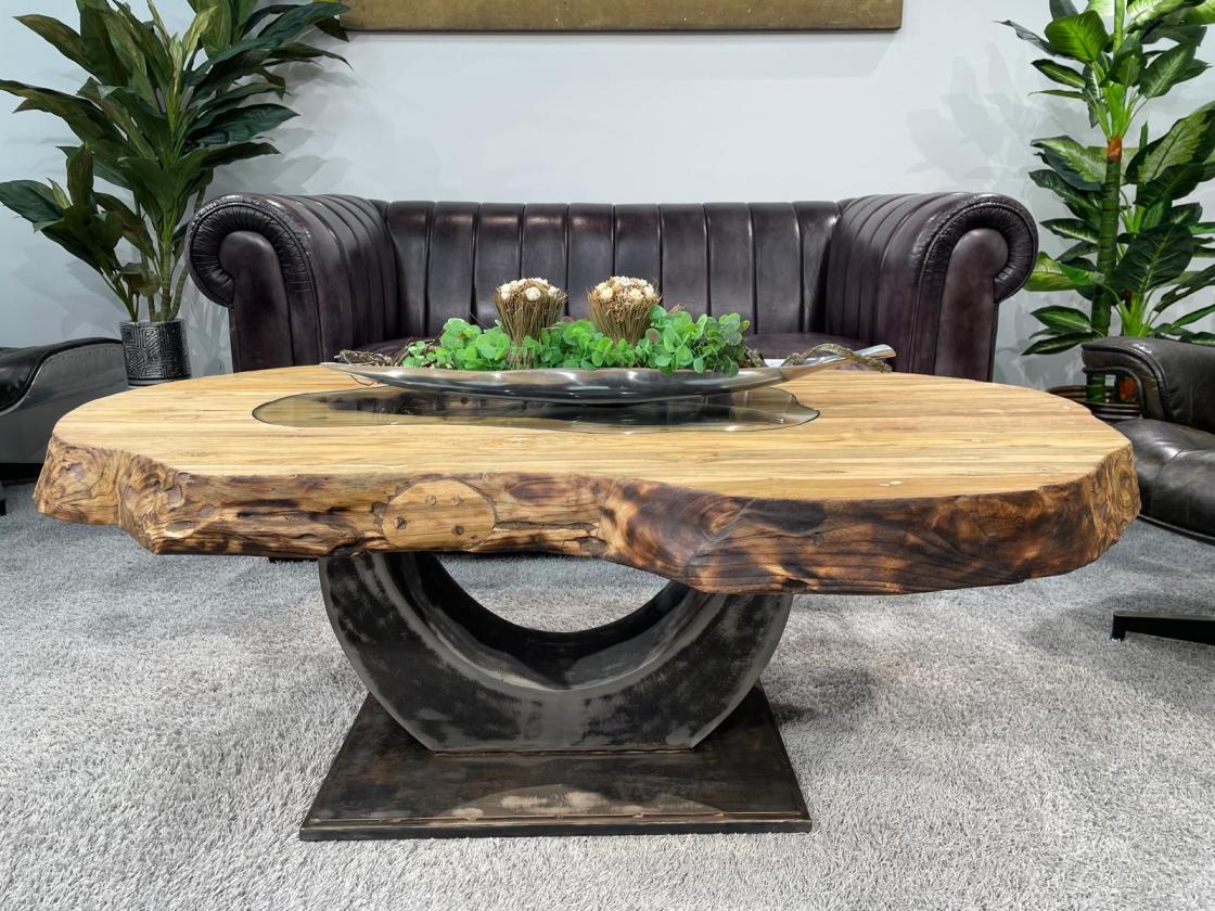 Oval wooden table with glass top and vase with pink flowers.