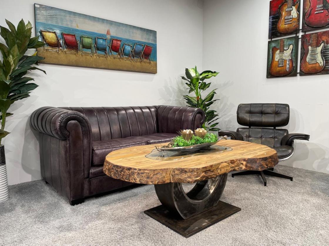 Organic wooden coffee table with glass top, vase with orchids.