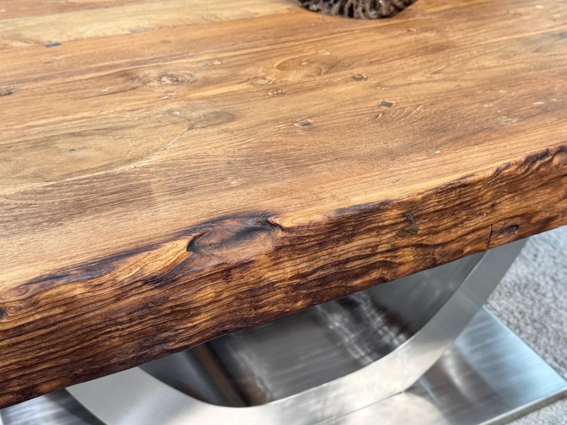 Close-up of a dining table with wooden top and raw steel frame.