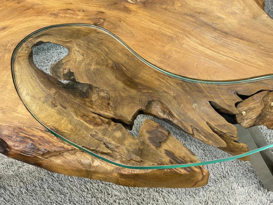 Tree trunk coffee table with glass top, irregular shape.